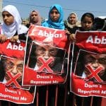 Palestinians hold a poster depicting Palestinian President Mahmoud Abbas during a protest against the blockade